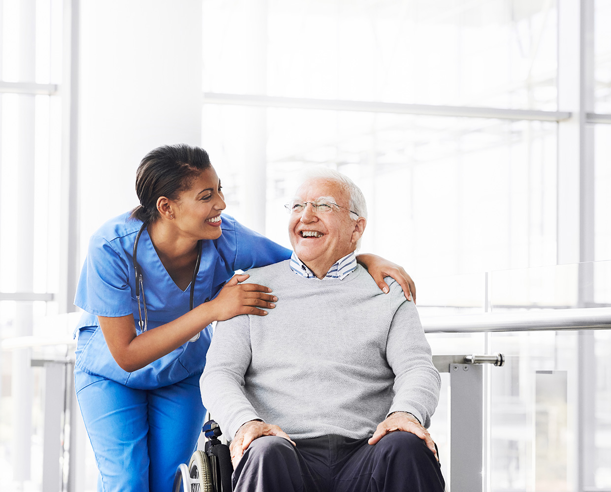 A nurse sharing a laugh with an older gentleman in a wheelchari