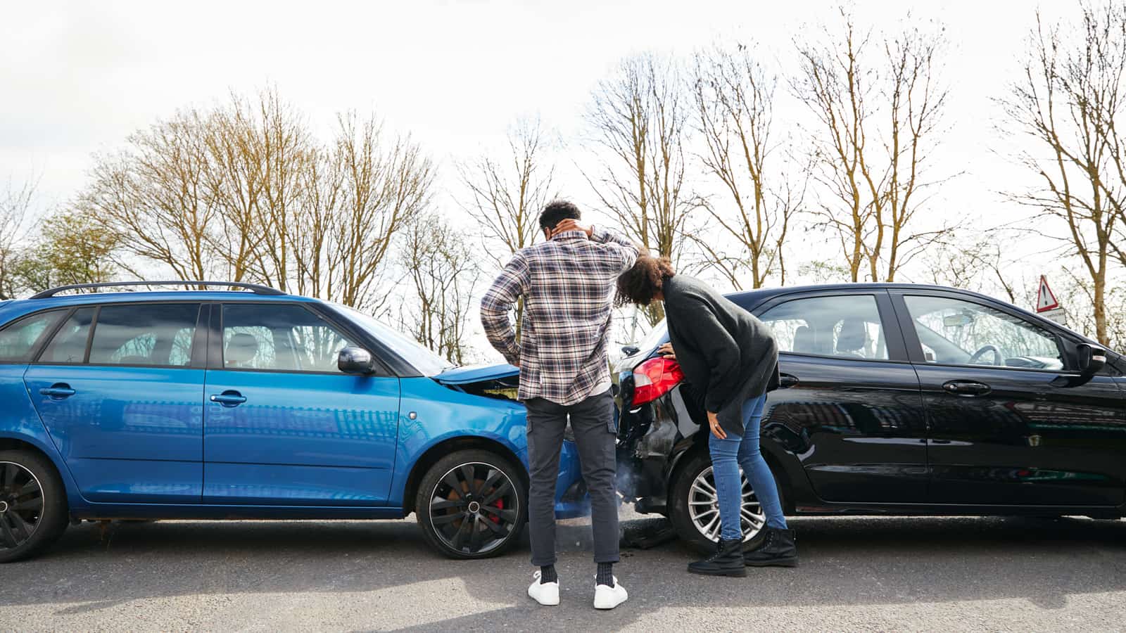 Man and woman looking over their cars after a wreck.
