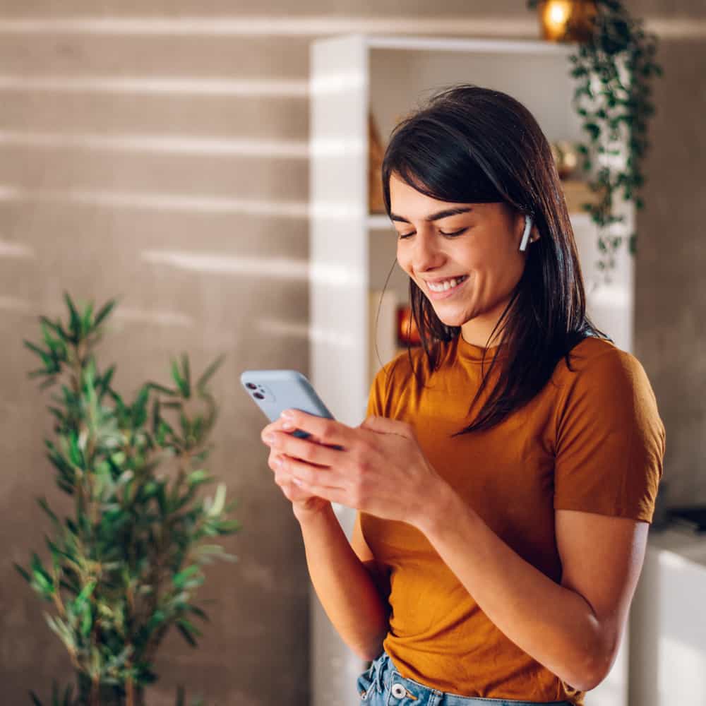 Young woman standing  looking at her phone.
