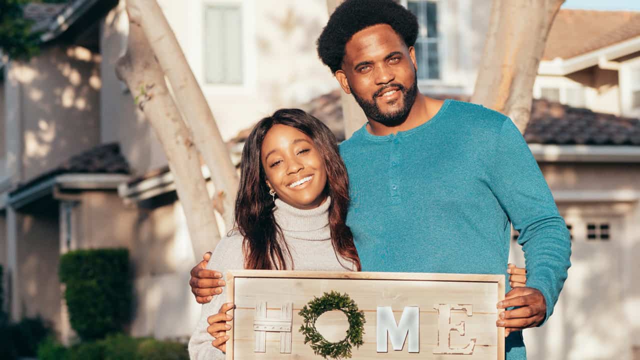 Husband and wife holding a Home Sweet Home sign