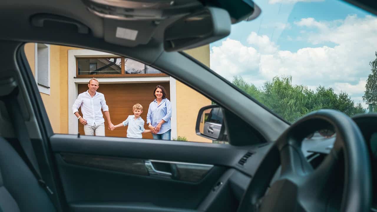 People in front of their house with their car