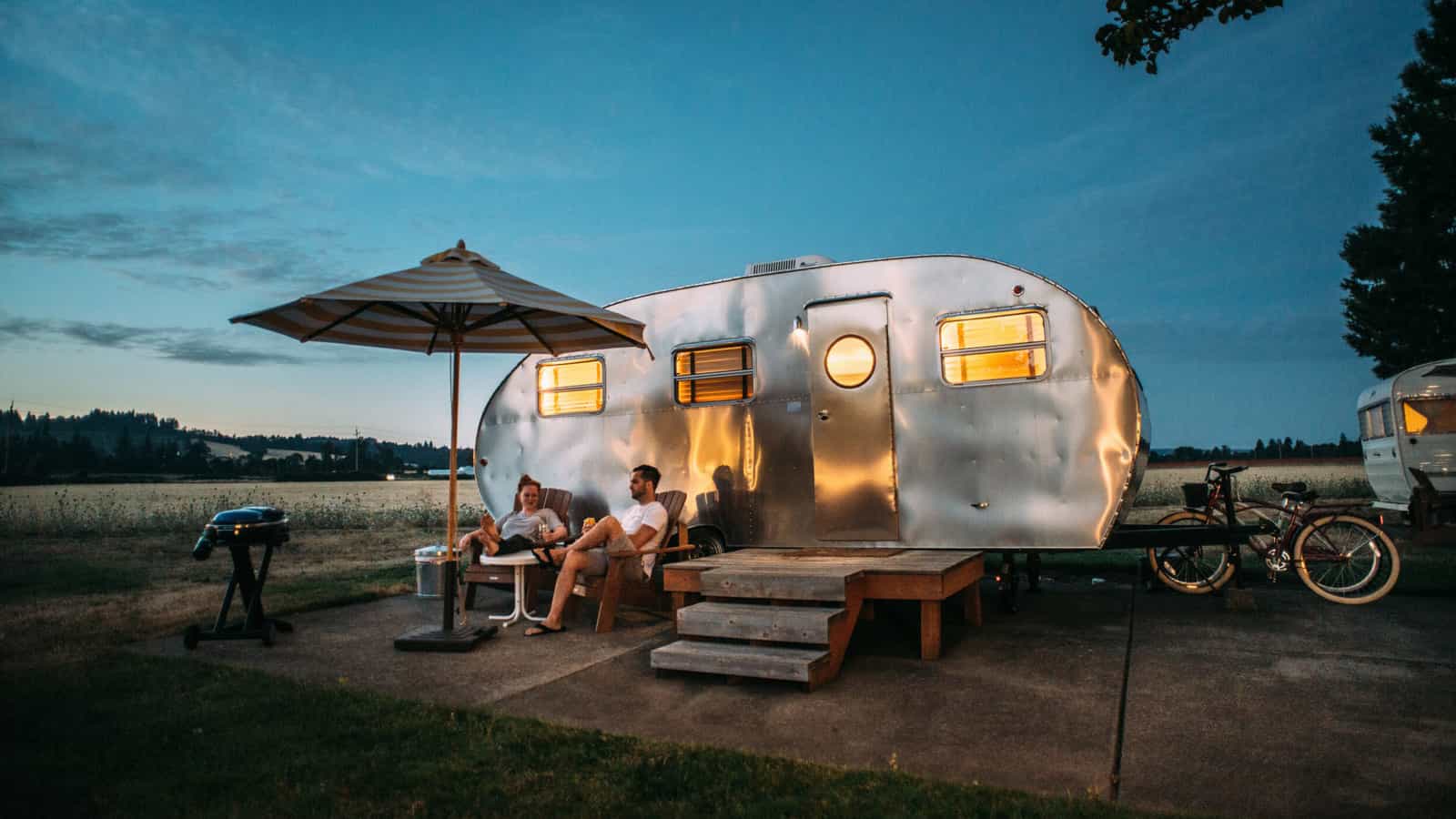 People sitting in from of Airstream camper.
