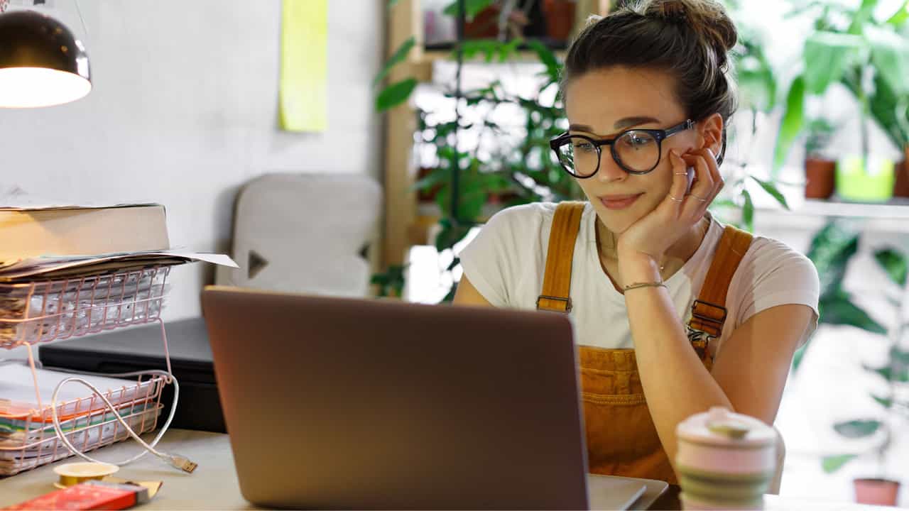Young woman looking at her laptop utilizing her e-services