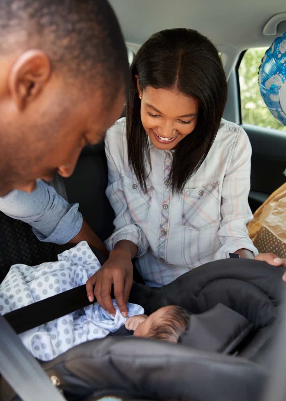 Family with a new baby sitting in their new car.