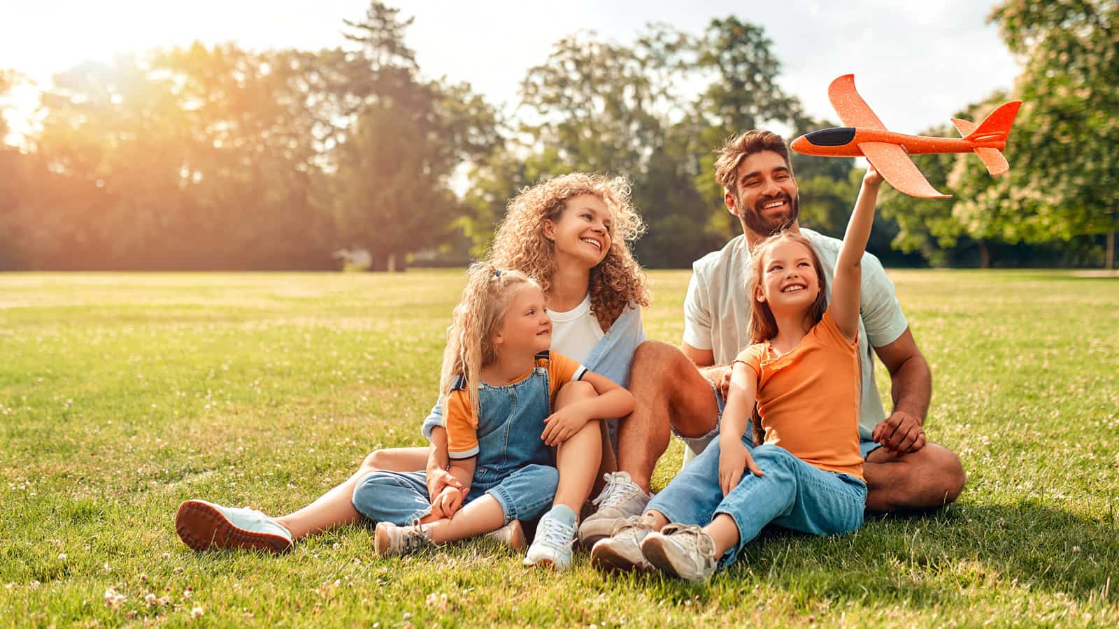 Mom and dad with two children sitting in a park.